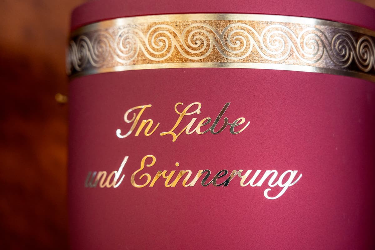 Bordeauxrote Urne mit der goldenen Inschrift „In Liebe und Erinnerung“