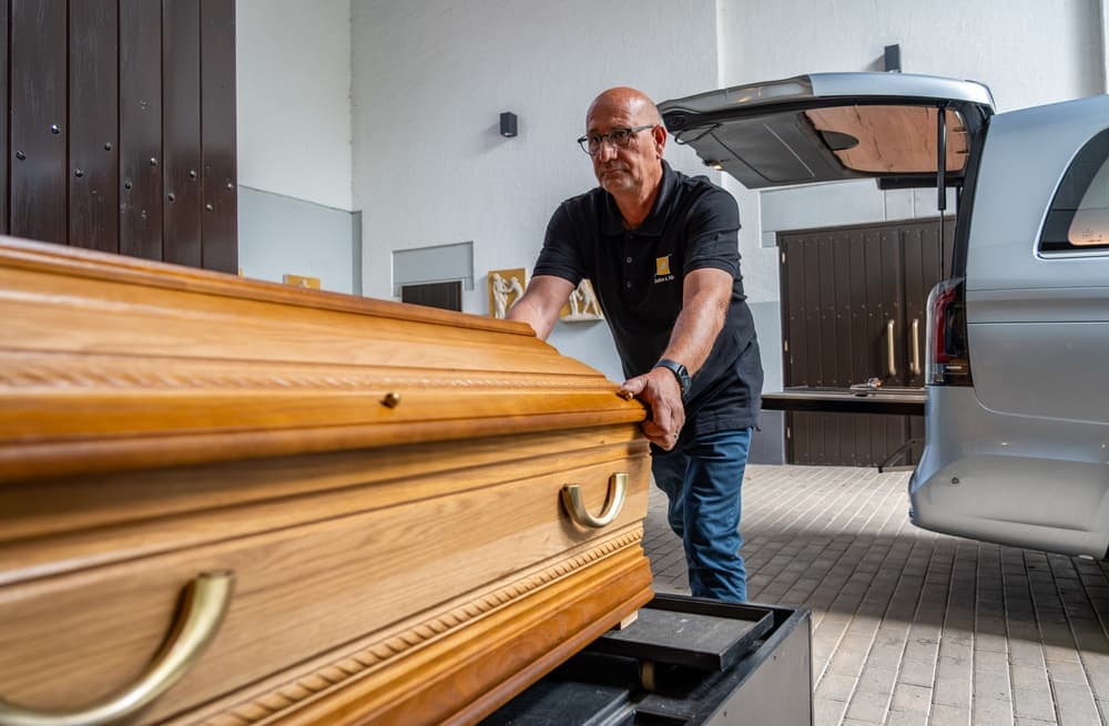 Ein Sarg wird zum Bestattungswagen gebracht